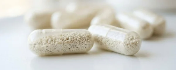 Transparent probiotic capsules resting on a clean white surface with soft natural light creating gentle shadows